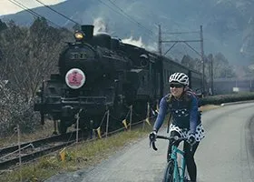 機関車と並走してサイクリングする女性